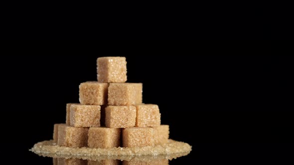 Demerara brown sugar cubes on black background rotating