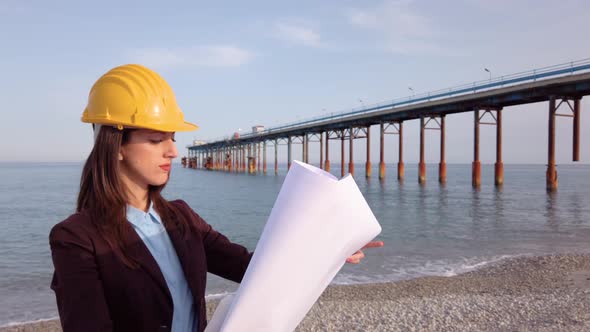 Female Engineer is Walking on the Beach near the Bridge