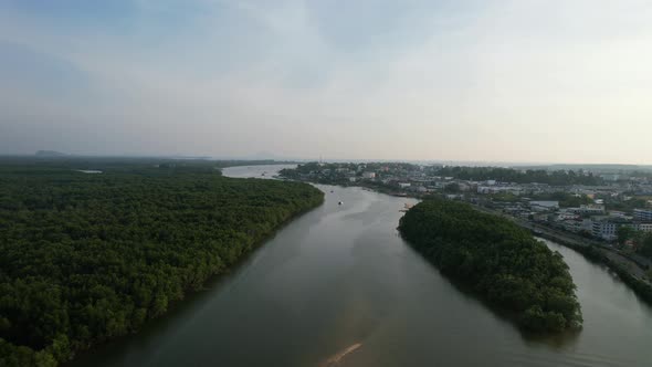 Aerial drone panning up over an island in the middle of a river and mangrove forest on a sunset afte