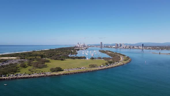 High revealing drone view of a man-made ocean inlet and safe boat harbor with a metropolitan skyline