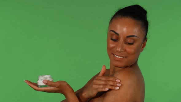 Attractive Mature Woman Using Body Lotion on Green Background