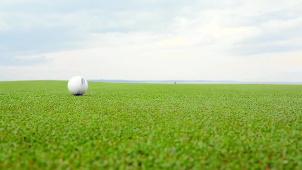 White Recycled Golf Ball Against the Skyline in the Background alt