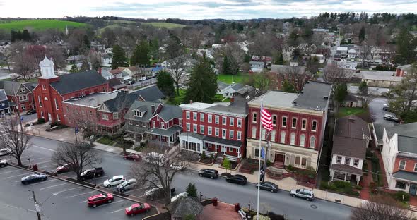 Aerial orbit of small town in USA. Town square on bright spring day. Traffic drives through city. Pe