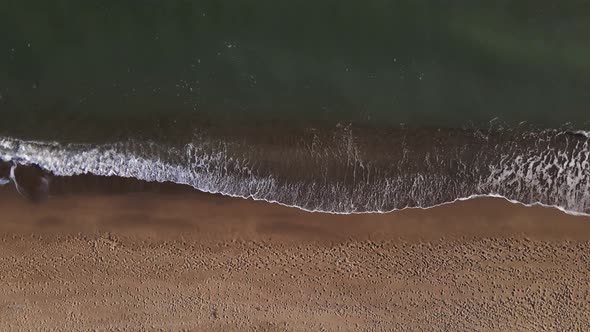 Aerial view of sandy beach and sea with waves