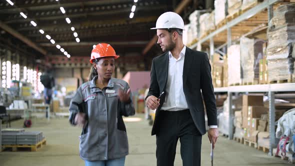 White man, boss and black woman, worker, walk through the production workshop