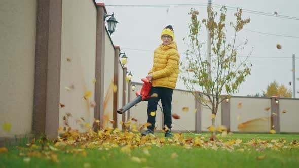 Teenage Boy Blowing Yellow Dry Leaves Straight to Camera Slow Motion Childhood