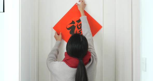 Woman sticking chinese calligraphy on the door