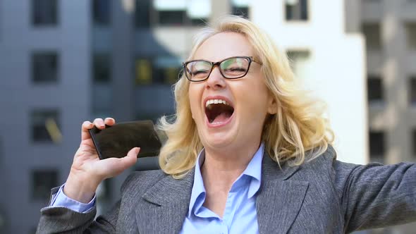 Mature Female Office Worker Rejoicing Good News From Phone About Raising Salary