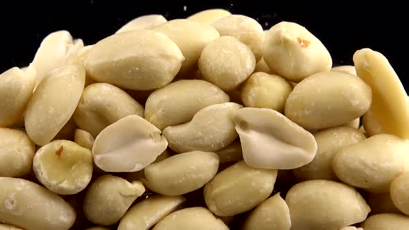 Falling blanched peanuts on a black background.