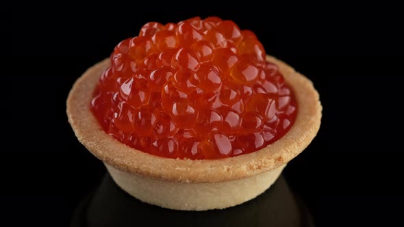 Snack with red caviar. Tartlet with red caviar close-up, rotation. 4K UHD video