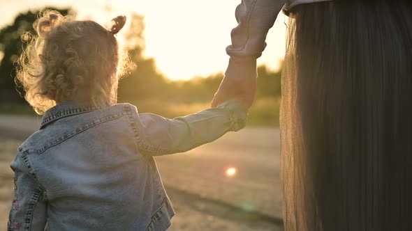 Mom reaches out and takes the hand of her little daughter, they walk together