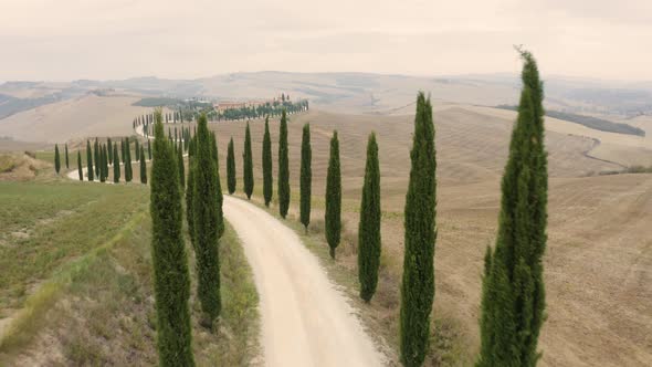 Aerial view passing by of small road crossing mountain countryside, Italy.