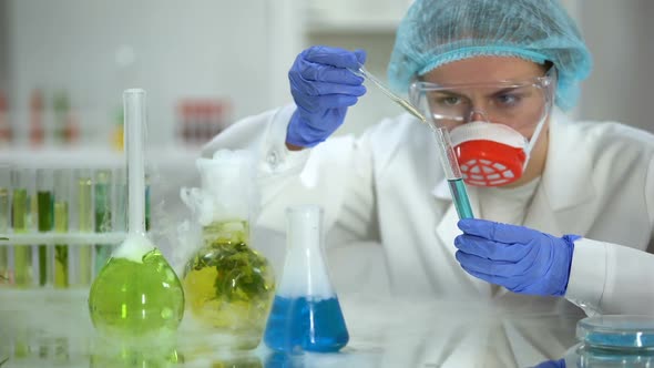 Biochemist Pouring Oily Liquid in Tube With Blue Substance and Checking Reaction