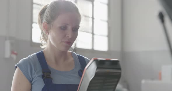 Female mechanic doing a car service, she is checking the air filter