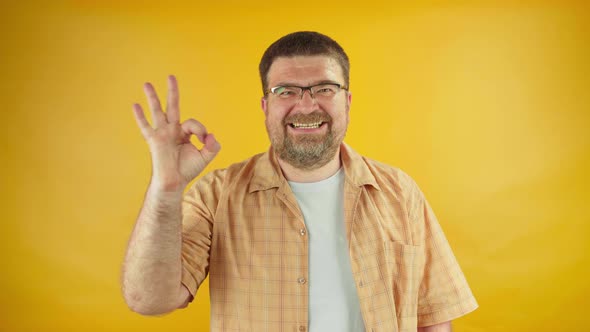Adult male in eyeglasses showing ok gesture on camera, high salary, big win, credit.