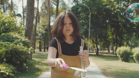 Portrait of Elementary Age School Girl Playing with Bubbles in Park