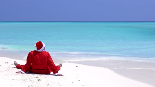 Santa Claus Sitting on the Beach with Outstreched Hands. Christmas Holidays