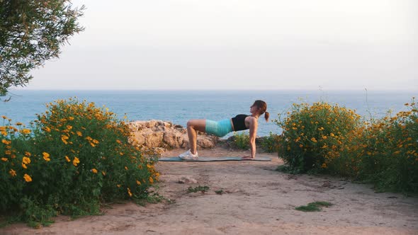 A Young Woman Exercising on Yoga Mat By the Sea