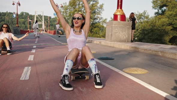 Portrait of Two Teenage Girls Riding on City Bridge Sitting on Skateboards Youth Culture Bright