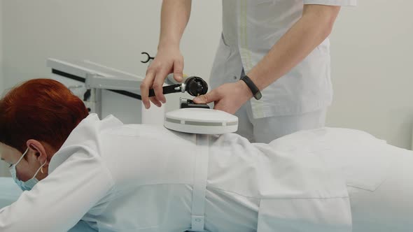 the Doctor Performs a Shock Wave Therapy Procedure to Treat the Patient's Back