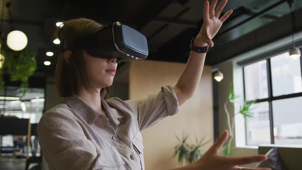 Asian businesswoman standing using vr googles in a modern office