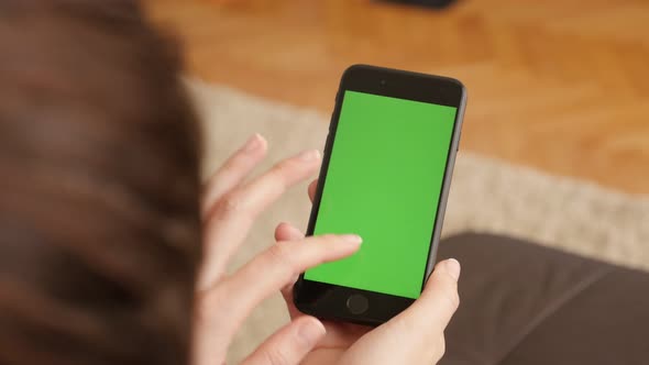 ZAJECAR, SERBIA - OCTOBER  2016 Finger gestures of female over green screen modern phone in living r