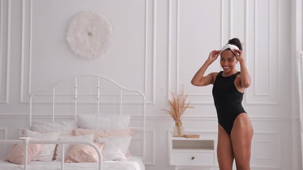 Dark Skin Woman in Headband Dancing and Smiling in Bedroom Falling on a Bed