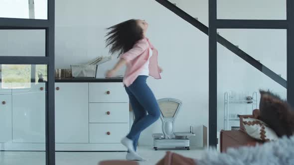 Young Cheerful Caucasian Girl Dancing in Kitchen and Smiling. Portrait of Happy Brunette Woman