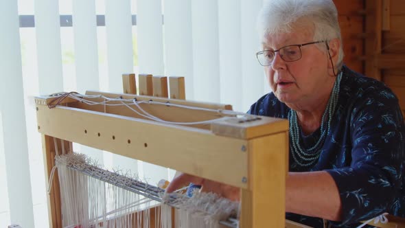 Senior woman operating weaving machine 