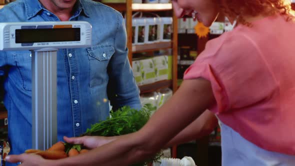 Smiling female staff weighting vegetables on scale