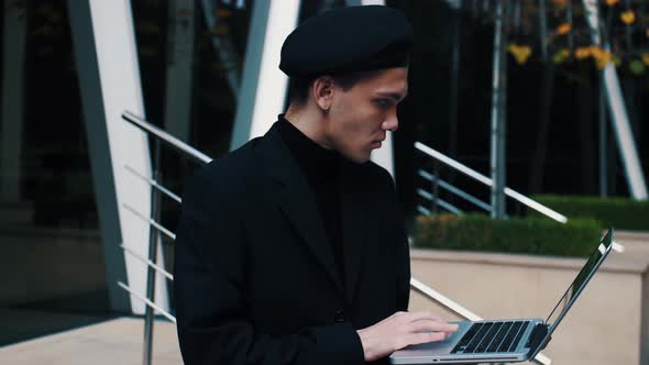 Handsome Young Businessman Sitting on the Stairs Outdoors Working with His Laptop. 