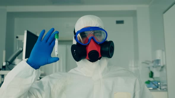 Person in Hazmat Holds a Tube with a Sample for Coronavirus