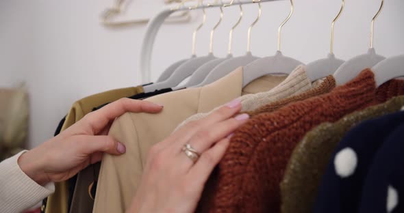 Woman shopping looking through different clothes, blouses and dresses in a departmental clothing sto