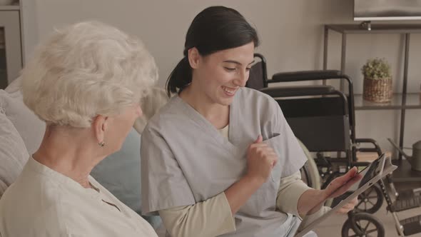 Social Worker Explaining Senior Woman How to Use Digital Tablet