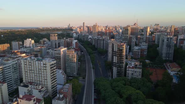 Dolly in flying over train rails near park in Belgrano neighborhood whith river in background, Bueno