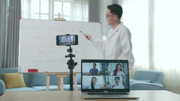 Asian Male Teacher Teaching Chemist Online At Home With Students On Laptop Screen