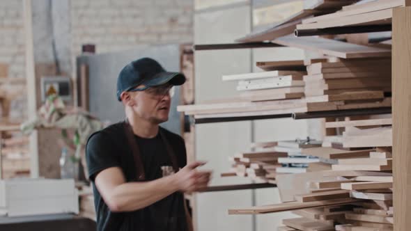 Man in a Carpentry Workshop Takes a Triangular Wooden Piece From the Shelf