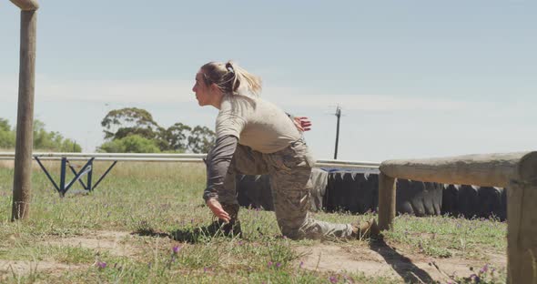 Fit caucasian female soldier going over and under hurdles on army obstacle course