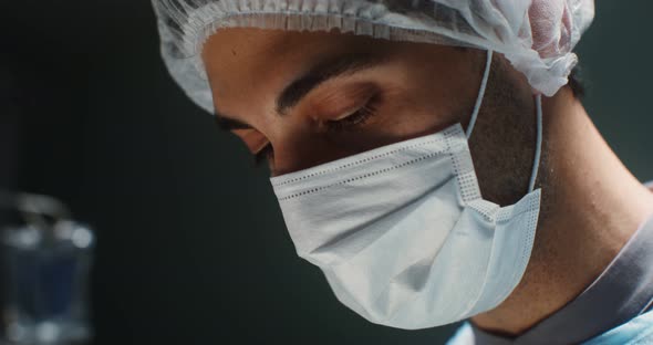 Closeup of a Doctor's Face in a Medical Mask and a Disposable Cap on His Head