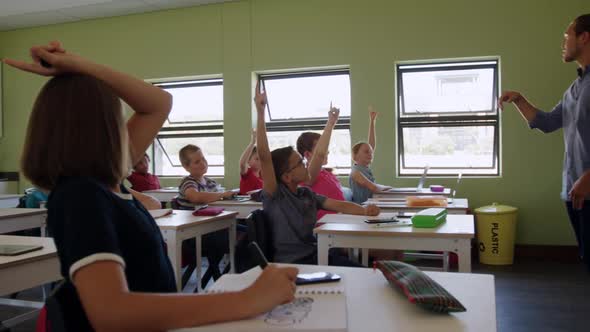 Group of kids raising their hands in the class