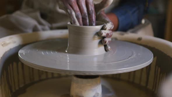 Close up view of female potter creating pottery on potters wheel at pottery studio