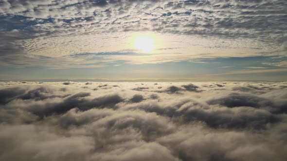 Aerial View of Bright Yellow Sunset Over White Dense Clouds with Blue Sky Overhead