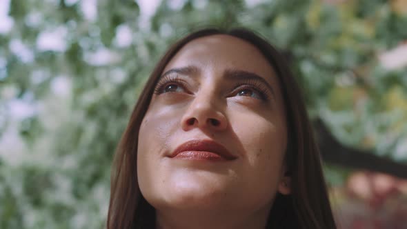 Close up of young woman looking around appreciating view of flower blossoms