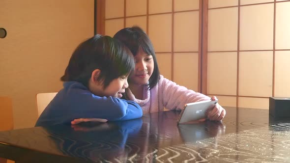 Cute Asian Children Using Smartphone In Living Room