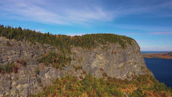 Aerial footage pushing in towards cliff face on Kineo Mountain in peak autumn foliage