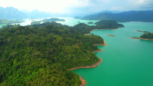 A drone flying over a dam in a beautiful tropical forest.