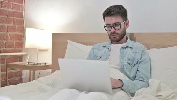 Young Male Designer Working on Laptop and Taking Nap in Bed 