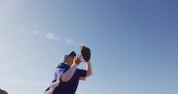 Mixed race female baseball fielder catching and dropping ball on sunny baseball field