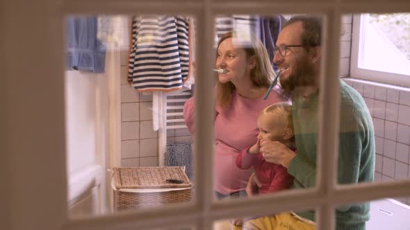 Family brushing teeth together on authentic bathroom.