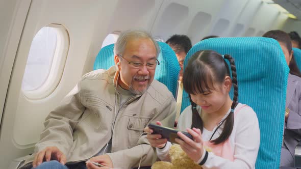 Asian grandfather and daughter sitting on board travel for holiday trip together by airplane.